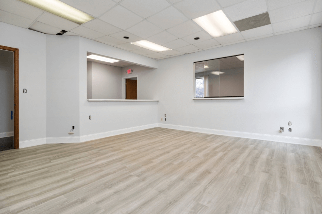 Sala comercial reformada com instalação de Piso Vinílico tom madeira clara em Palmas pela Tecfloor, com acabamento de rodapé branco e recepção.