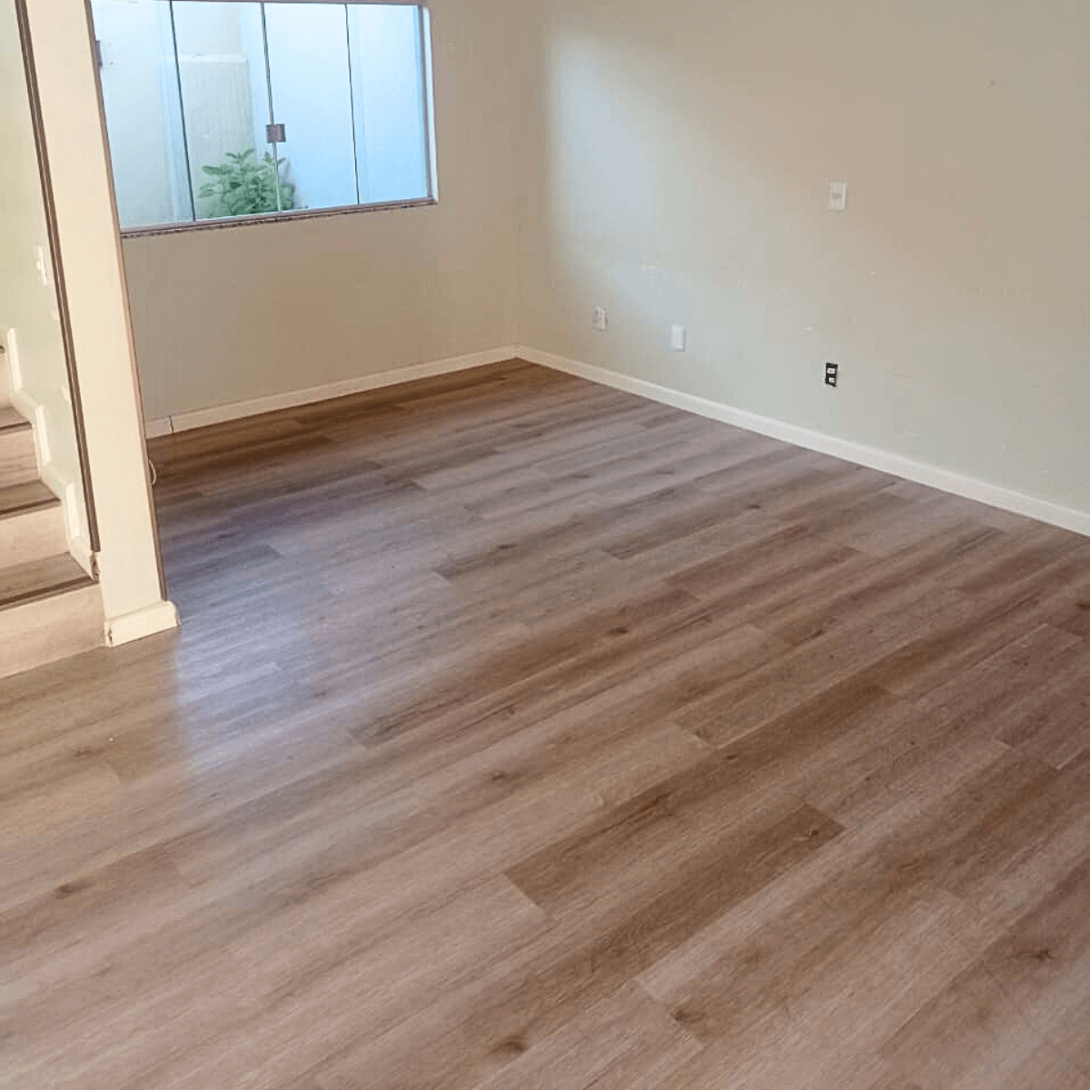 Sala residencial com instalação de piso vinílico amadeirado e acabamento de rodapés brancos em Palmas, Tocantins.