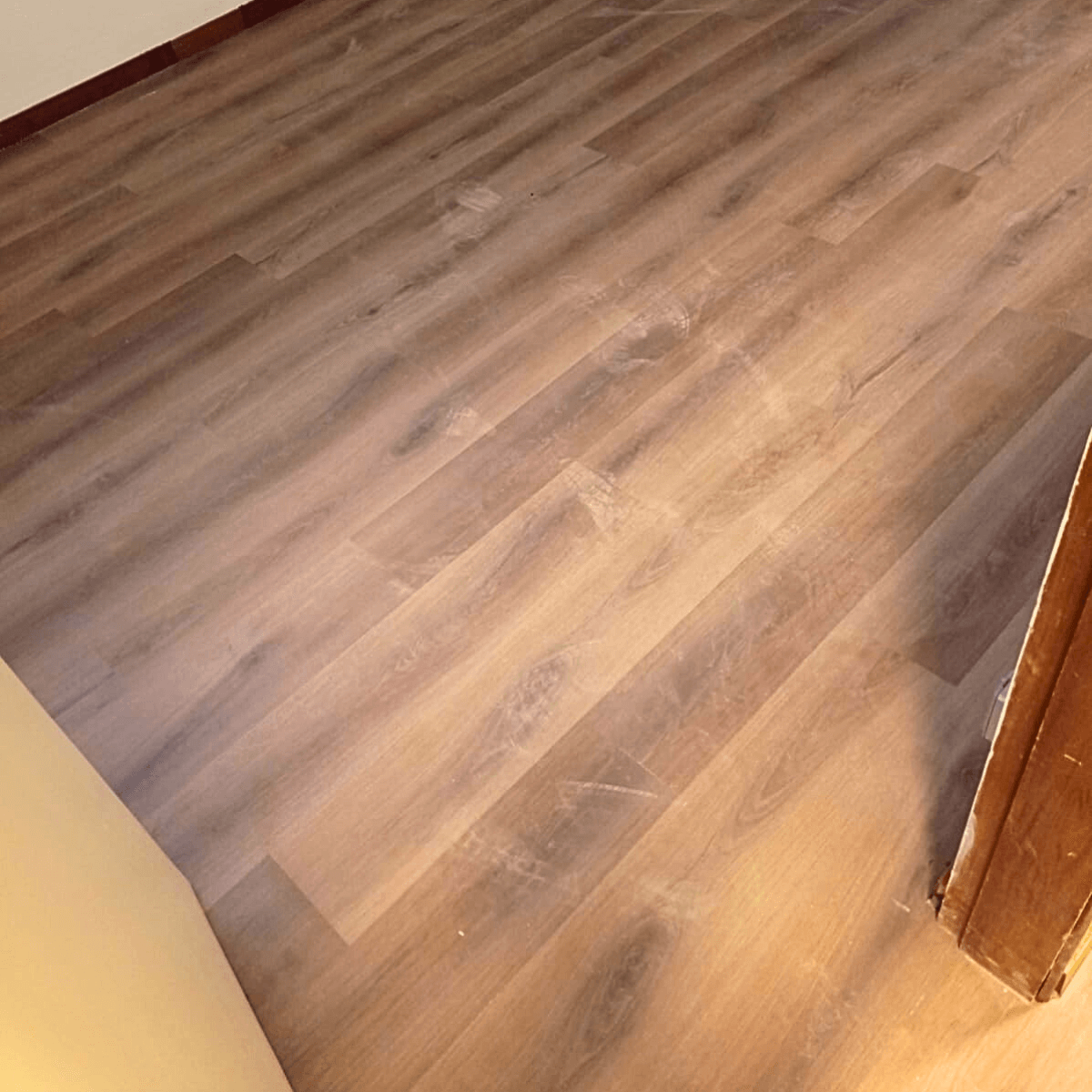 Detalhe da textura de piso laminado amadeirado escuro, demonstrando a qualidade do material.