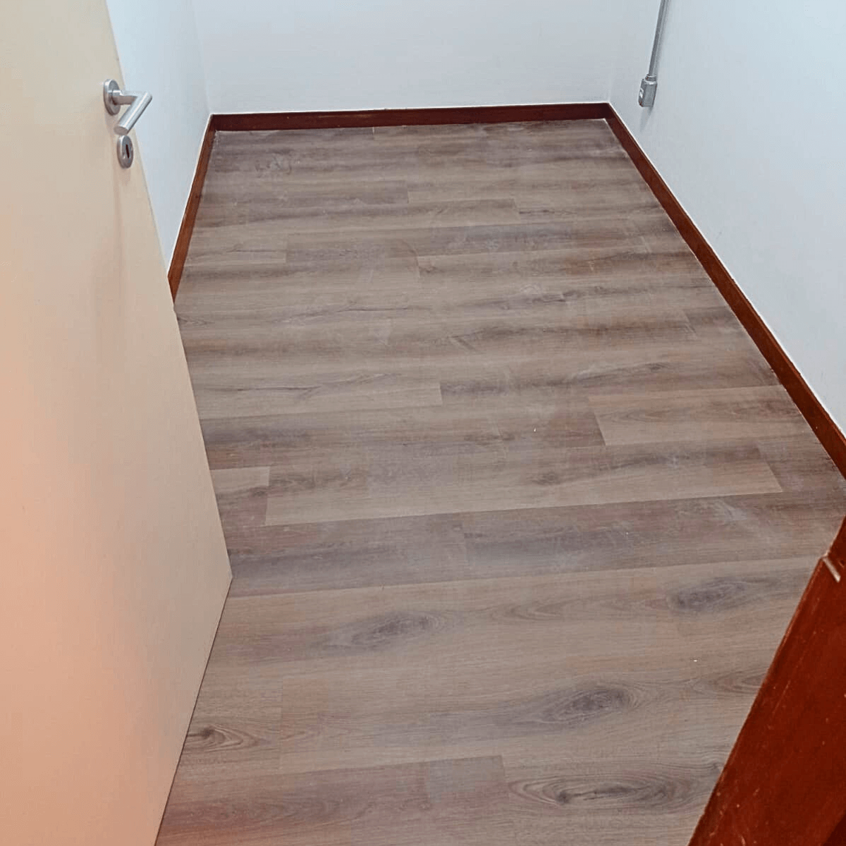 Dormitório finalizado com revestimento de piso laminado claro, pronto para mobiliar.