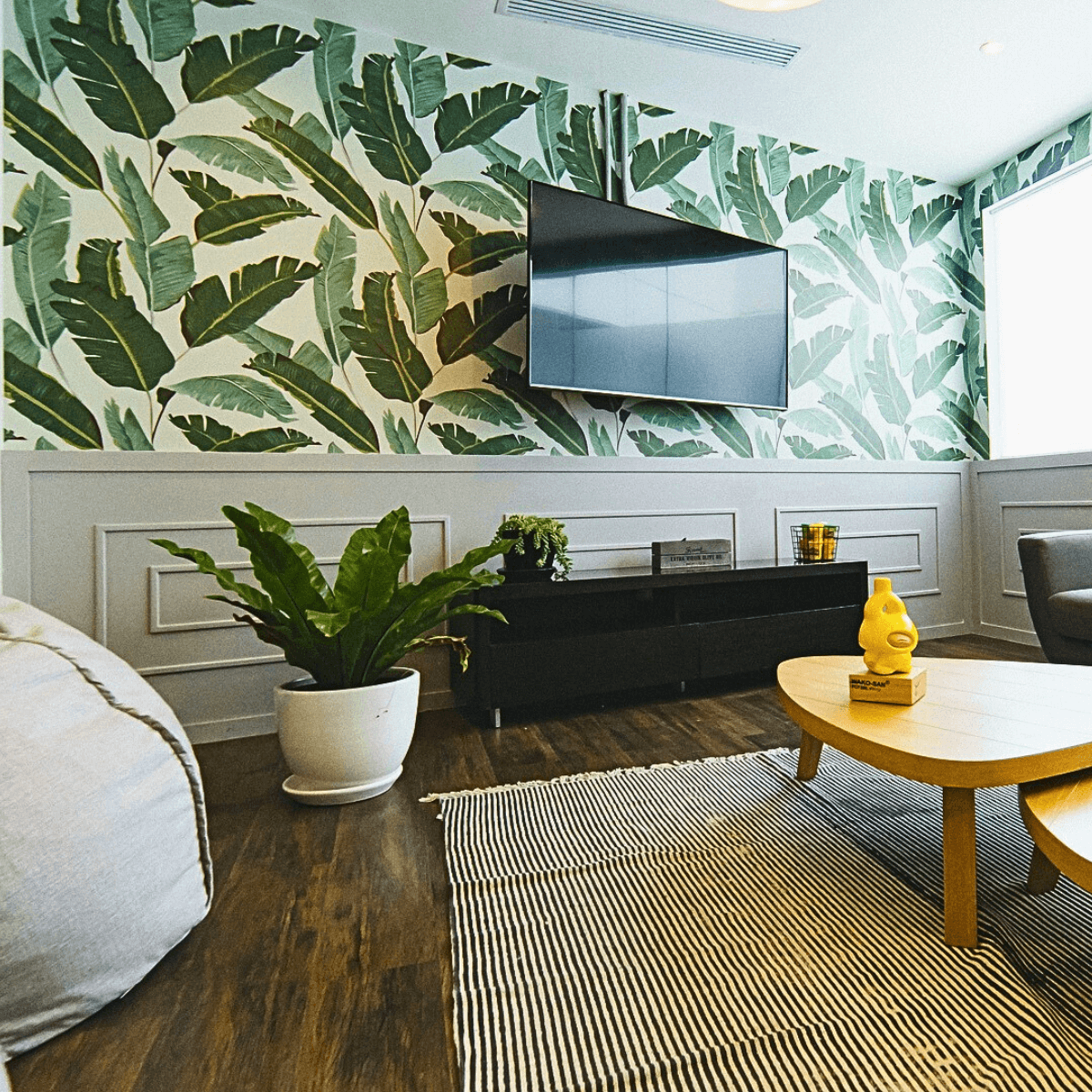 Sala de estar sofisticada com papel de parede botânico e piso de madeira escura restaurado.