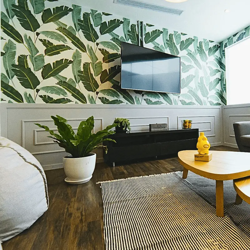 Sala de estar sofisticada com papel de parede botânico e piso de madeira escura restaurado.